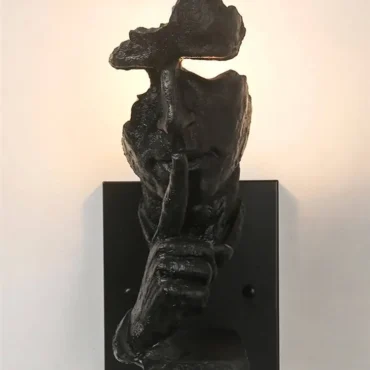 Fauske black resin wall light with face and hand design