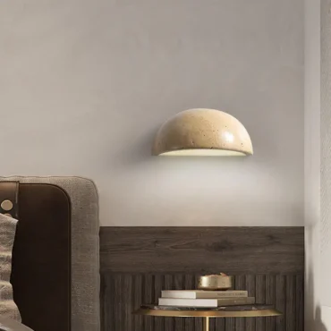 Kjerstad travertine half-moon wall lamp mounted above a bookshelf