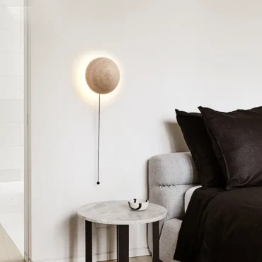 Gjøvik travertine wall light mounted above a bedside table in a bedroom
